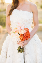 torso of a bride holding a bouquet