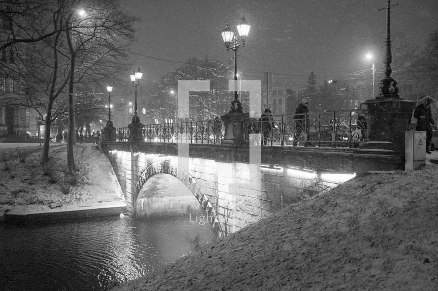 pedestrians walking across a bridge a night in winter 