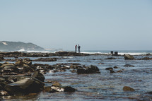 people standing on a rocky shore 