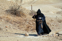 Hermit walking through the desert. Religious concept of enlightenment through fasting and prayer.
