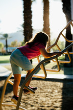 a little girl climbing up playground equipment 