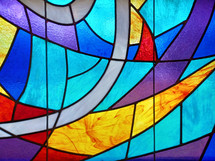 Stained glass window with blue, red, gold and shades of light and dark blue and purple colors. 