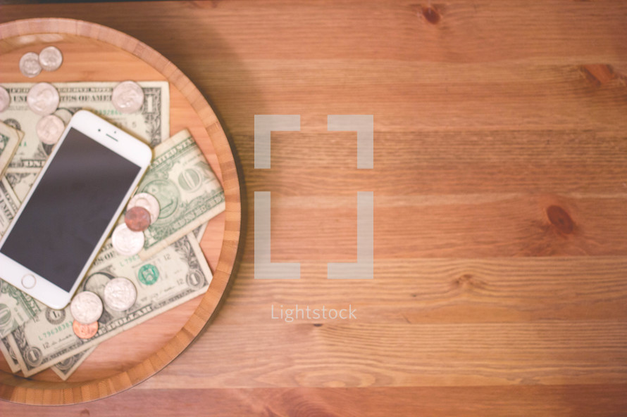 iPhone and money in a wood bowl 