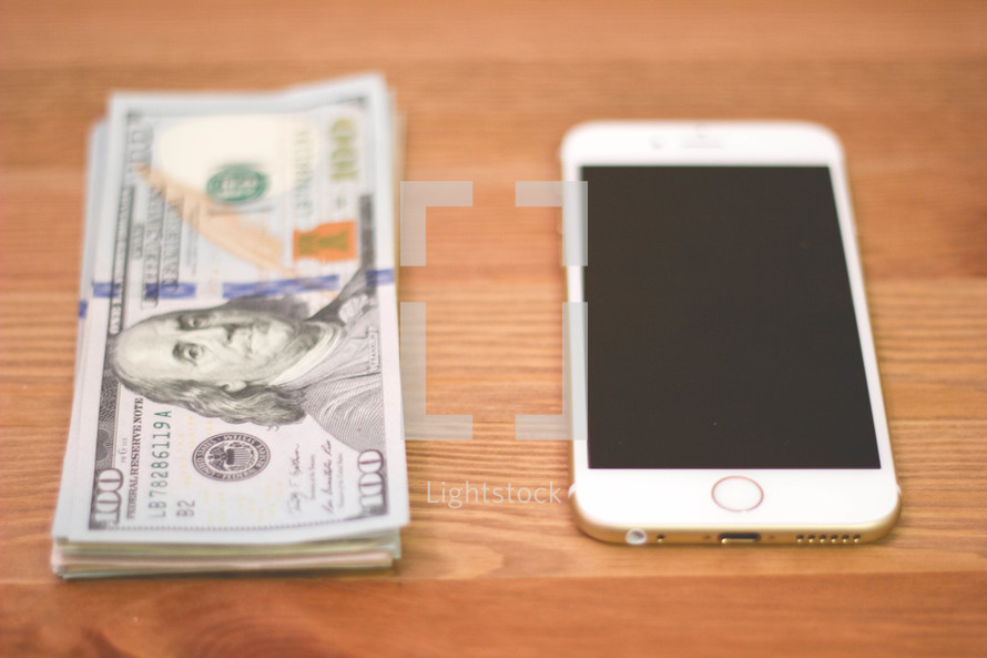 stack of one hundred dollar bills and iPhone 