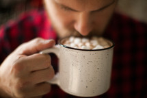 man in a plaid shirt drinking hot cocoa 