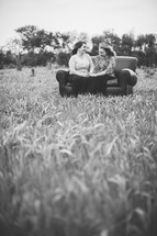 mother and daughter in conversation sitting on a couch outdoors in a field