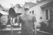 man holding a shovel and looking up 