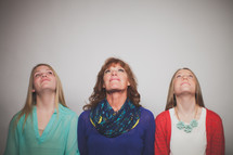 Mother and daughters looking up.