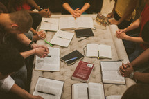 praying hands over Bibles at a Bible study