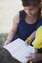 Mother and daughter reading the Bible outside.