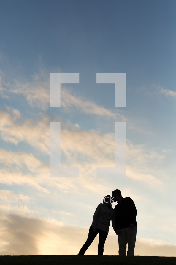 couple kissing with sky background