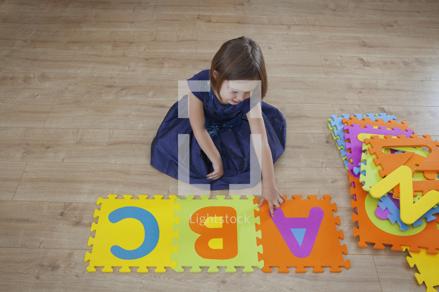 A young girl playing with letters of the alphabet viewed from above themes of learning education alphabet