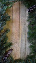 Border of Spruce branches on wooden background with pine cones