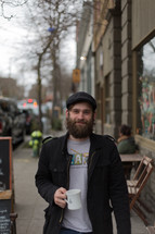Bearded man at an outdoor coffee cafe.