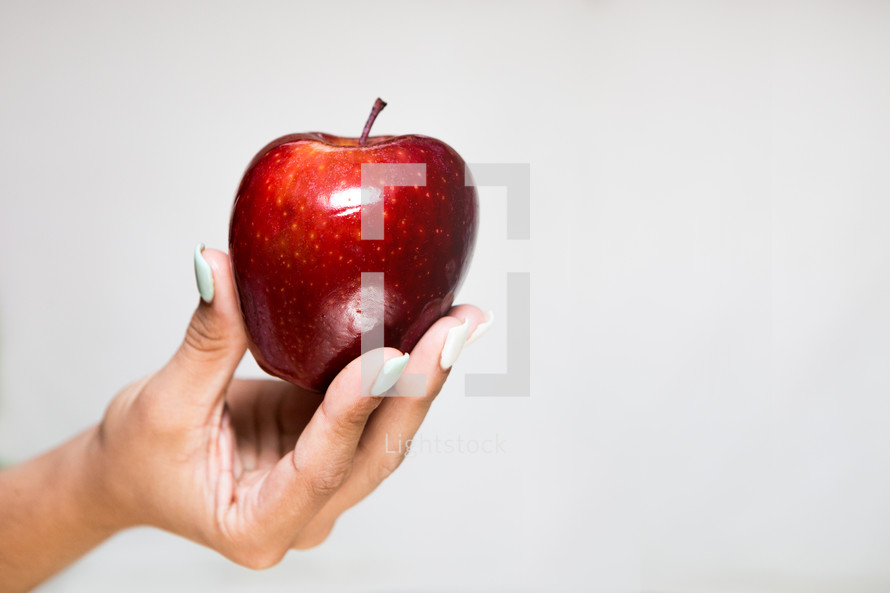 female hand offering a red apple 