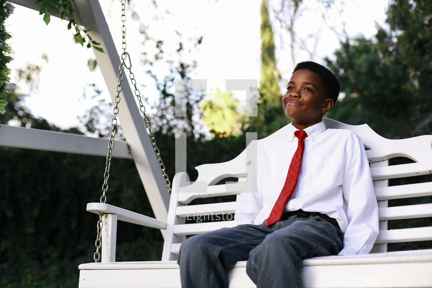 a boy in a tie sitting on a swing 