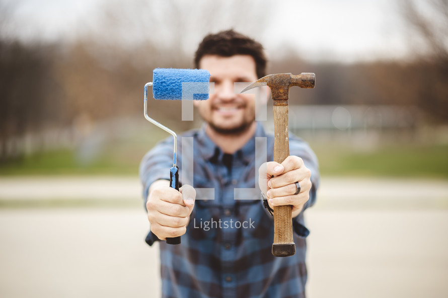 man holding a paint roller and hammer 