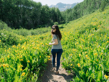 woman walking on a path through a field of yellow flowers 