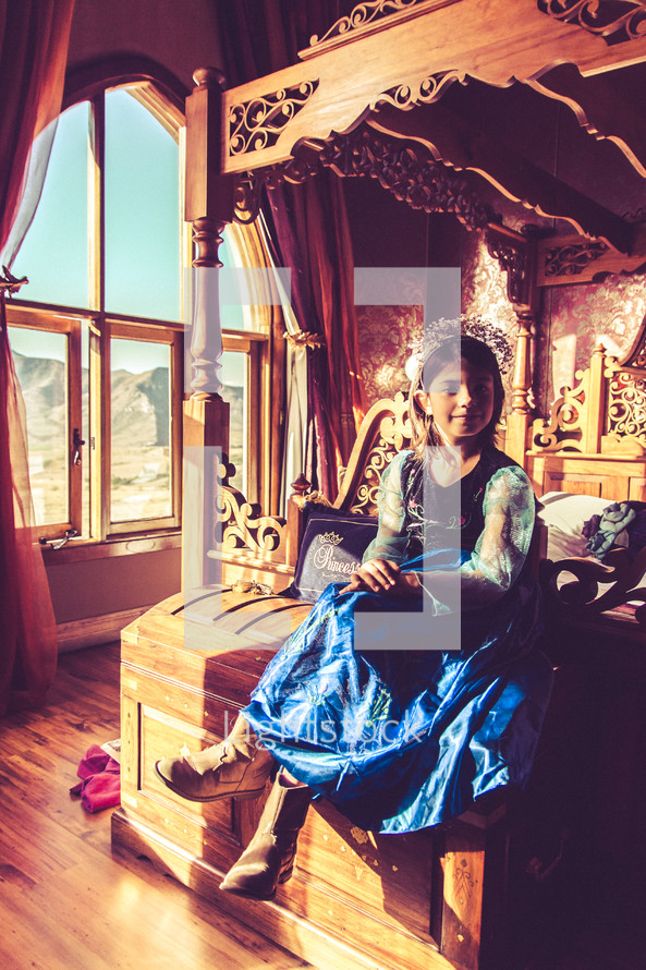 a girl sitting on a bed in a castle dressed up like a princess 