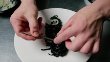 Hands Plating First Course Black Ink Squid Spaghetti Food At Restaurant