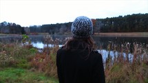 a woman standing at the edge of a pond 