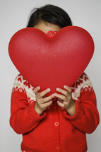 a child in a red sweater holding a red heart