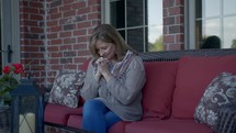 a female praying on a porch 