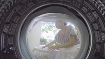 A view from inside a washing machine of a woman putting in clothes