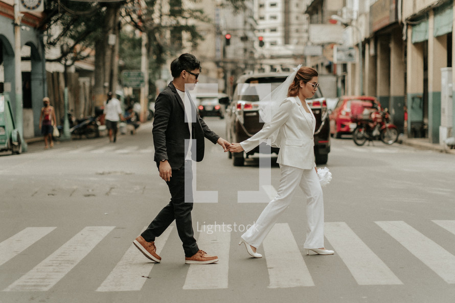 bride and groom crossing a crosswalk in a city 