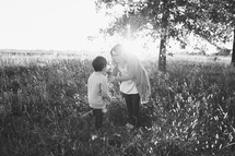 mother and son standing in a field outdoors 