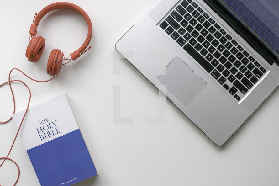 headphones, Bible, and laptop on a desk 