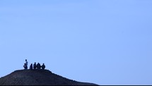 men sitting at the top of a desert hill 