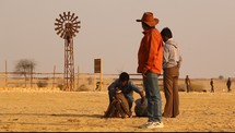 man building a fire and a windmill in a desert 