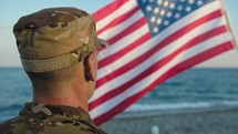 United States Marines military stand with salute against american flag on the beach