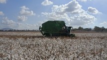Aerial tracking footage of cotton harvester in a large scale cotton field during harvest