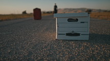 file box and suitcase in the middle of a road 