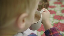 child coloring a Christmas coloring page and drinking hot cocoa 