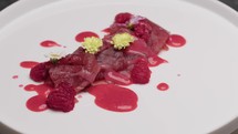 Gourmet appetizer of tuna carpaccio in raspberry sauce