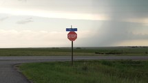 Stop sign, traffic sign on highway in midwest, rural America in Kansas farmland with distant storm clouds and cattle, cows in pasture.