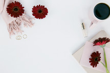 scarf, pink, blush, red gerber daisies, nail polish, coffee mug, stationary, white background, gold rings, pencil 
