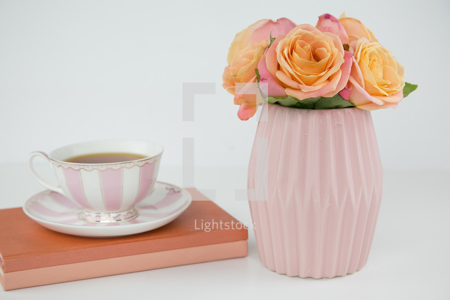 tea cup, book, and roses in a vase 