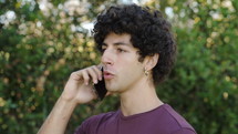 a young man talking on a cellphone outdoors 