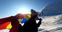 Woman running with a Romanian Flag on top of The Bucegi Mountains in Romania.