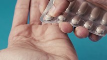 Hand of a Man Who is Taking a Pill Capsule From the Box at Home Dropping Down