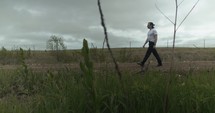 Young man walking on unpaved, dirt road on summer day explore, hiking, worshipping and praying. Lifestyle, worship and prayer concept.