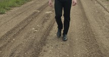 Feet of young man walking on unpaved, dirt road on summer day explore, hiking, worshipping and praying. Lifestyle, worship and prayer concept.