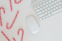 candy canes and computer keyboard with mouse on a desk 