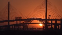 Silhouette pan of suspension bridge with sun in Long Beach California USA