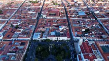 Aerial shot drone ascends over main square at sunset covered by clouds