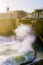 Waves crashing against stone wall in Jaffa, Israel